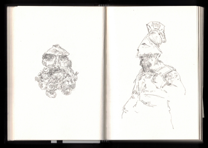 On the left, a sculpted bearded face, the forehead and everything but the face missing. On the right a greek soldier, helmet stuck high on the head, in armour, looking down.